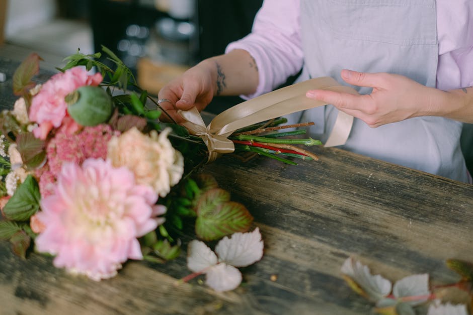 A close-up view of a floral arrangement featuring large, soft pink hydrangea blooms, creamy white roses, and delicate pale pink spray roses interspersed with sprigs of baby's breath and lush green euc