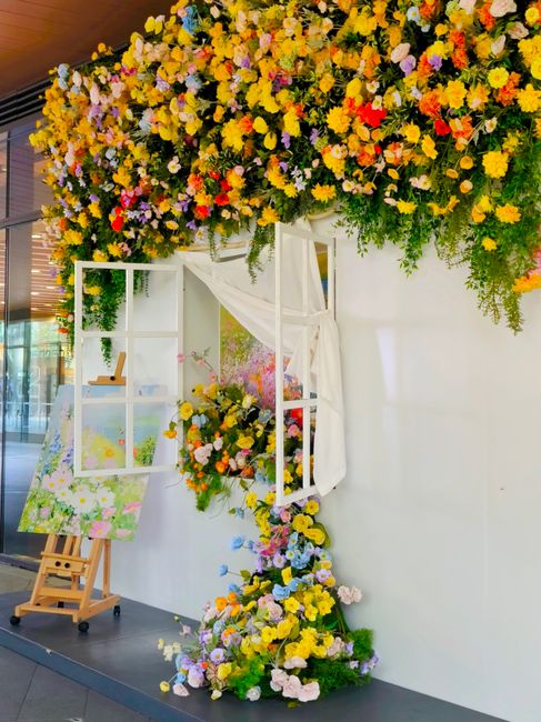 A close-up view of an elegant floral display featuring vibrant pink orchids and delicate cherry blossom branches arranged within geometric wooden frames. The flowers are fresh, with smooth petals and 